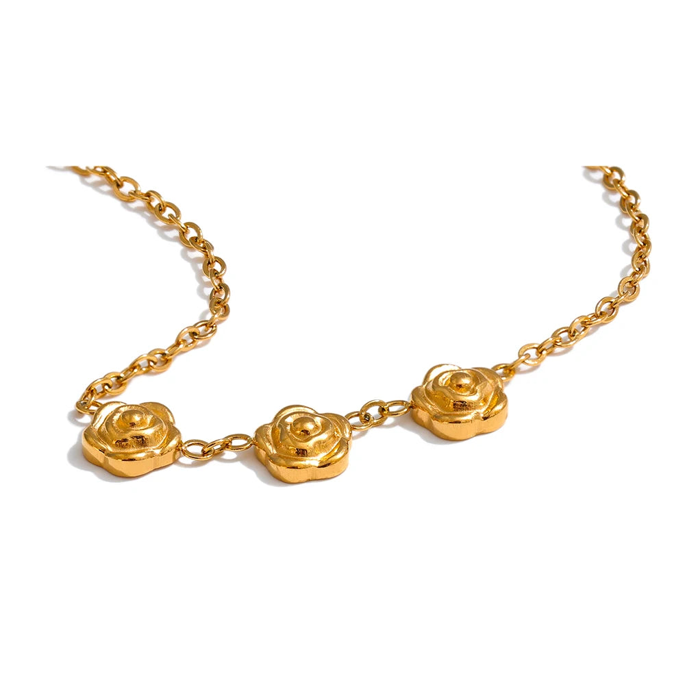 Guldhalsband i lågmäld men otrolig design av tre rosor i blänkande guld placerad på en vit bakgrund