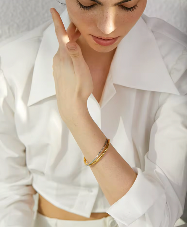 Armband i guld och silver som sitter på en mänsklig arm 